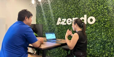 Specialists collaborating near the green wall at the Azendo office